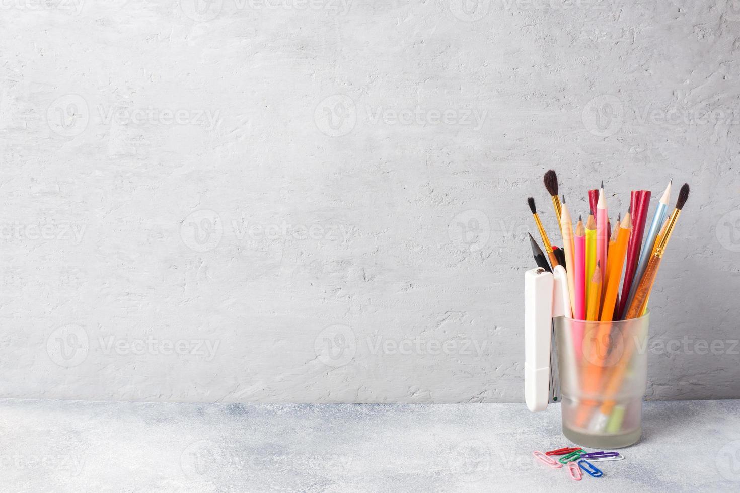 fournitures scolaires, un ensemble de marqueurs de crayon dans un verre sur une table grise avec une copie de l'espace. école conceptuelle. photo