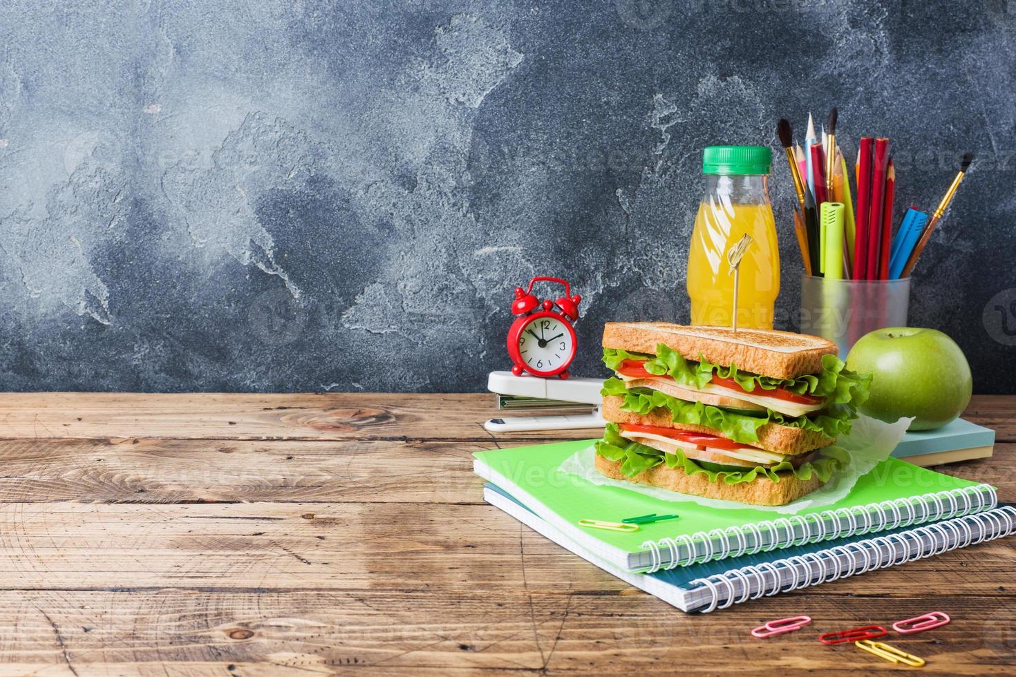 déjeuner sain pour l'école avec sandwich, pomme fraîche et jus d'orange. fournitures scolaires colorées assorties. espace de copie. photo