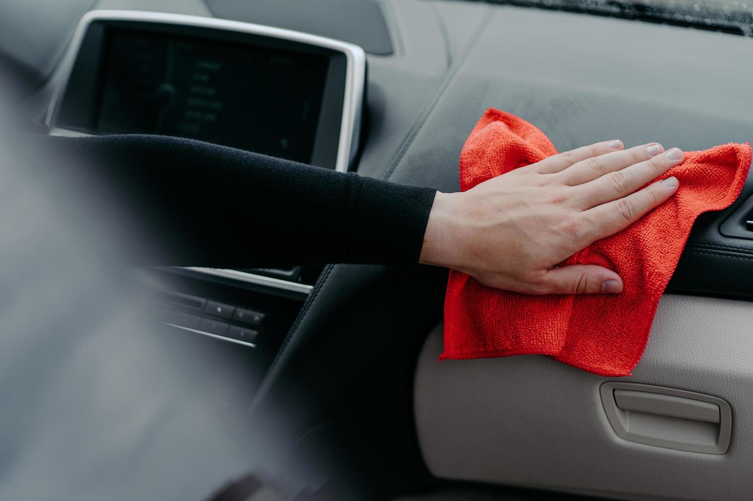 essuyant à la main l'intérieur de la voiture avec un tapis. concept de désinfection et de nettoyage. tuant le coronavirus sur la surface touchante de l'auto. concept de lavage de voiture console photo