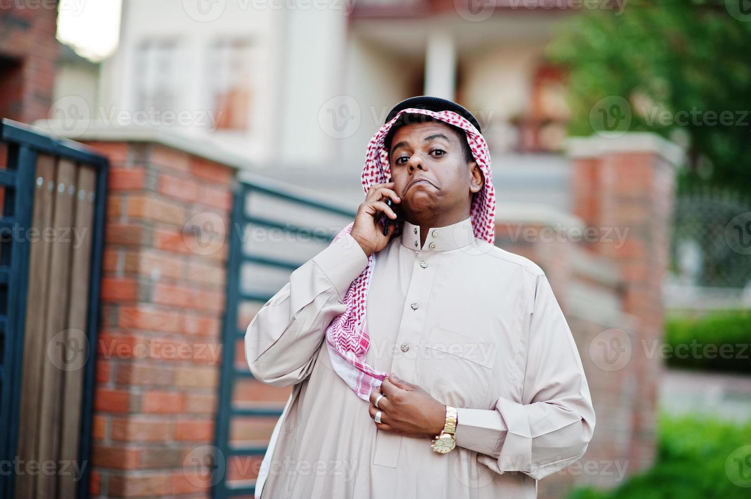 homme d'affaires arabe du moyen-orient posé dans la rue contre un bâtiment moderne avec téléphone portable et montrant des émotions surprises. photo