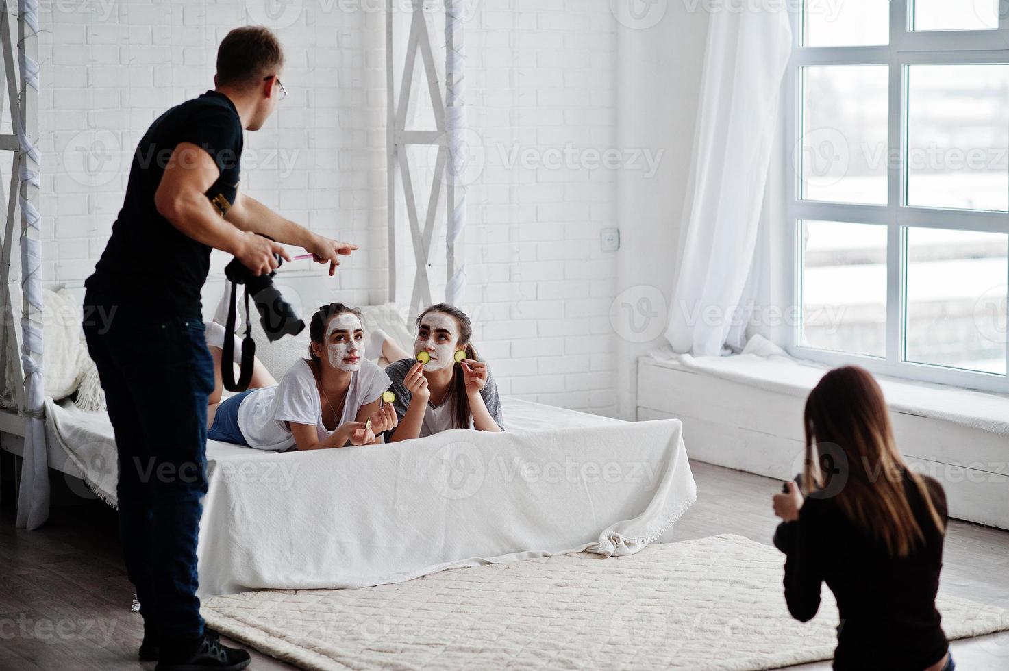 l'équipe de deux photographes prend des photos sur des jumelles en studio pendant qu'elles fabriquent leurs propres masques crème. photographe professionnel sur le travail.