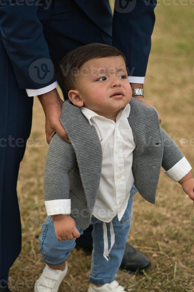 un père pakistanais asiatique tient son bébé de 11 mois dans un parc local photo