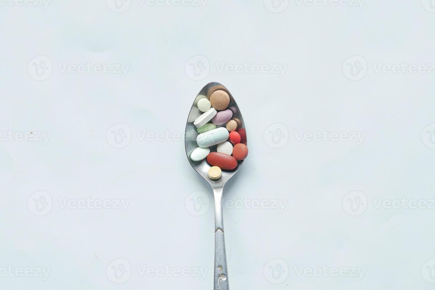 vue de dessus de nombreuses pilules et capsules colorées sur une cuillère blanche photo