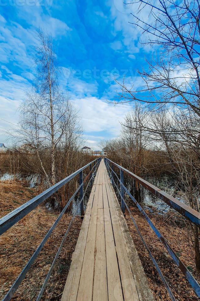 vieux pont de bois sur la rivière dans le village. passage piéton étroit. perspective. nature printanière en dehors de la ville. photo