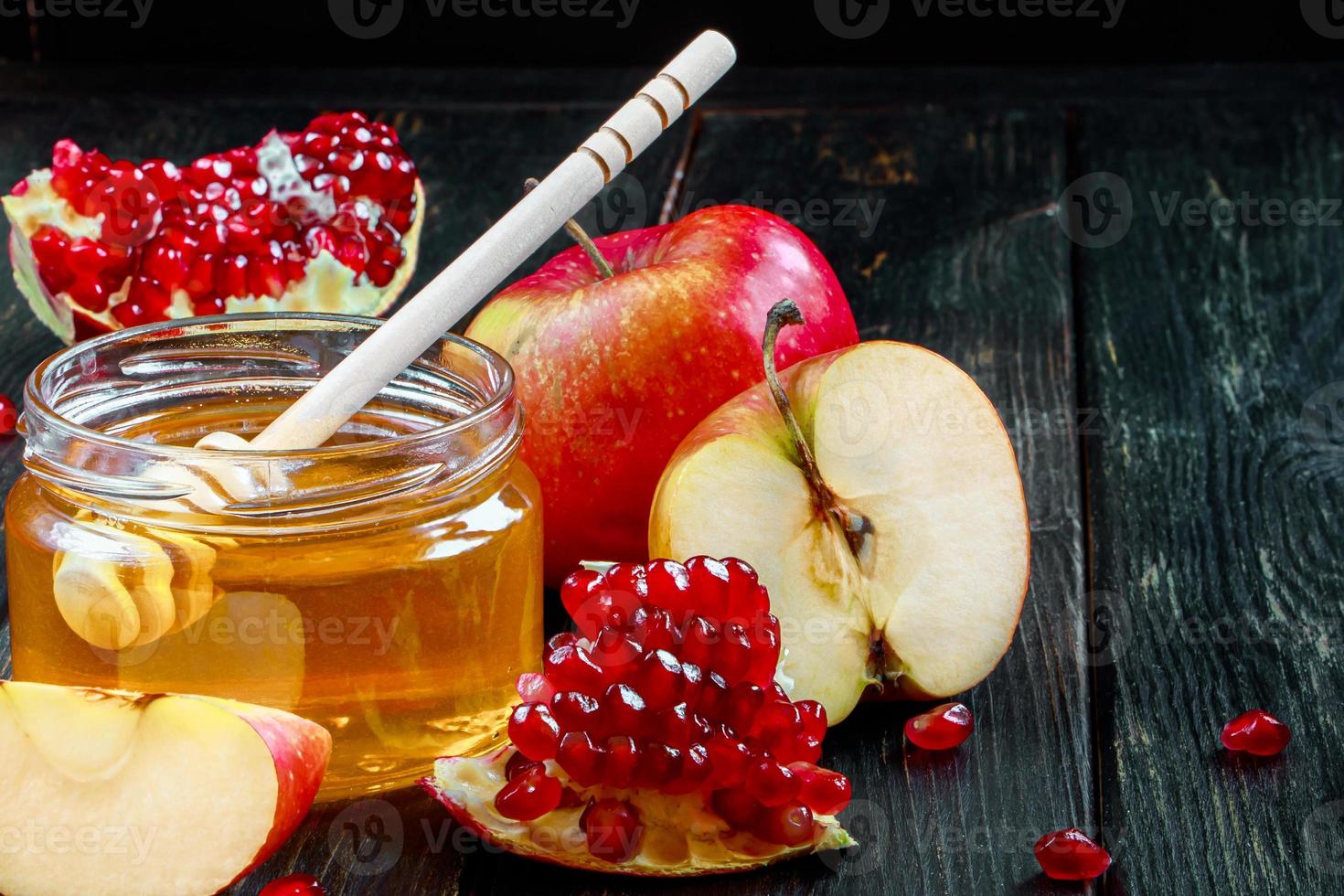 fête religieuse juive rosh hashanah. nature morte de pommes, grenades et miel sur fond de bois foncé. symboles traditionnels de célébration photo