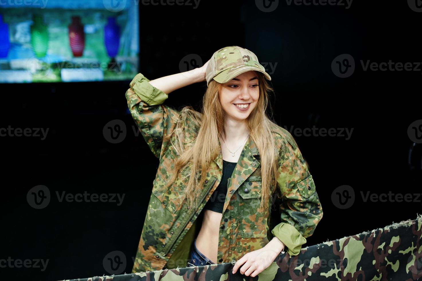 fille militaire en uniforme de camouflage sur fond de l'armée sur le champ de tir. photo