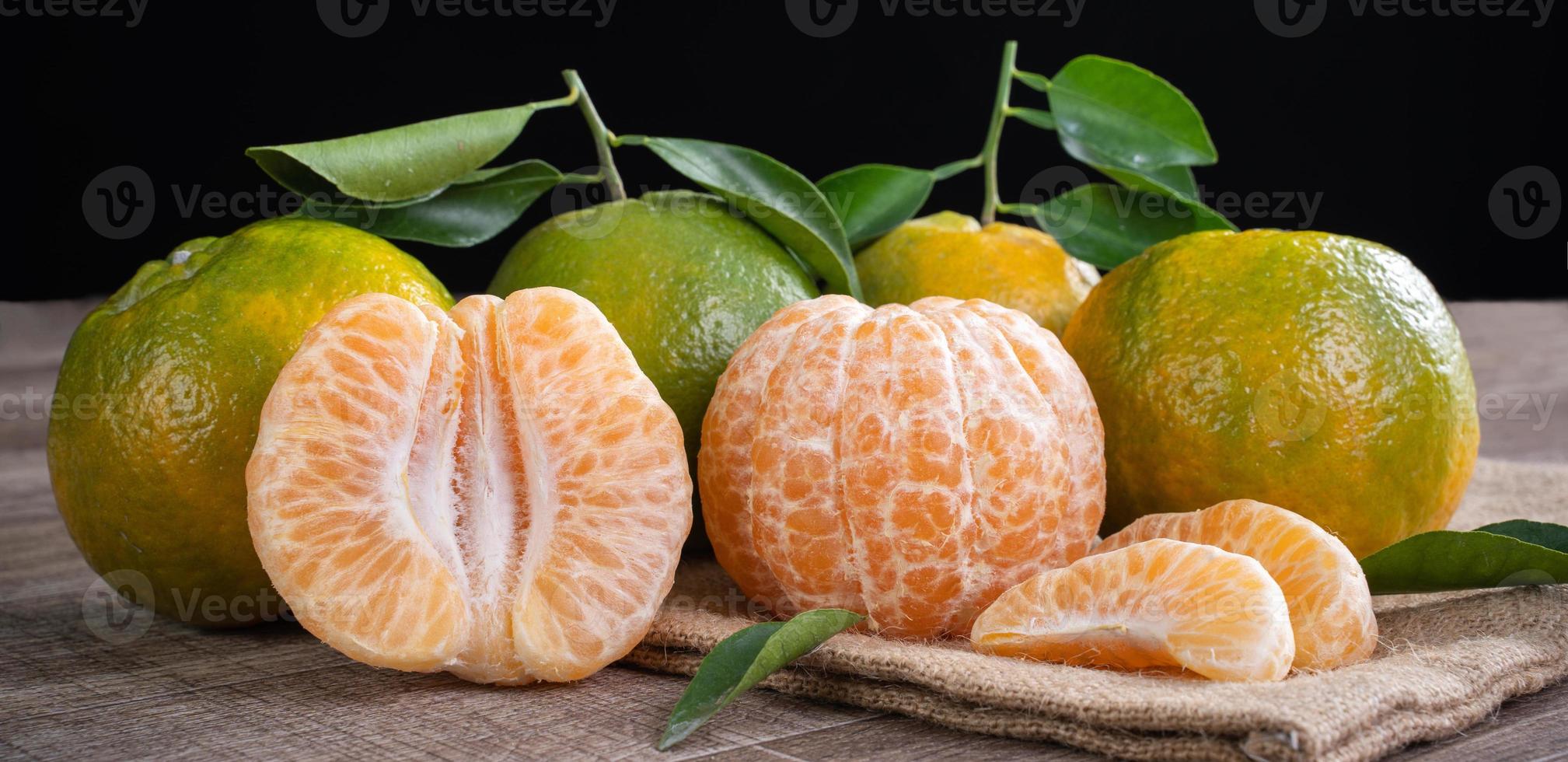 orange mandarine mandarine verte fraîche sur fond de table en bois foncé. photo