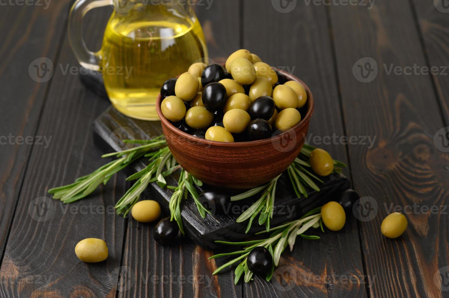 olives noires et vertes sur un fond rustique en bois foncé. photo