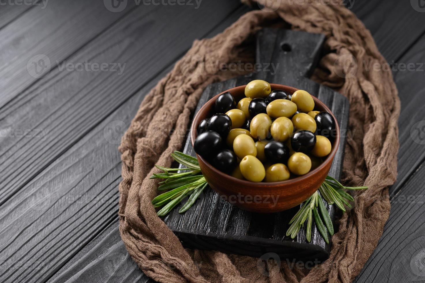 olives noires et vertes sur fond noir en bois foncé. photo