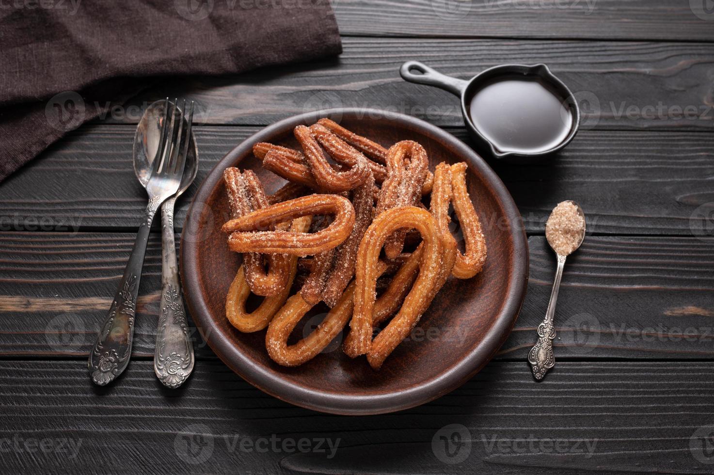 churros faits maison avec du chocolat sur un fond rustique en bois foncé. photo