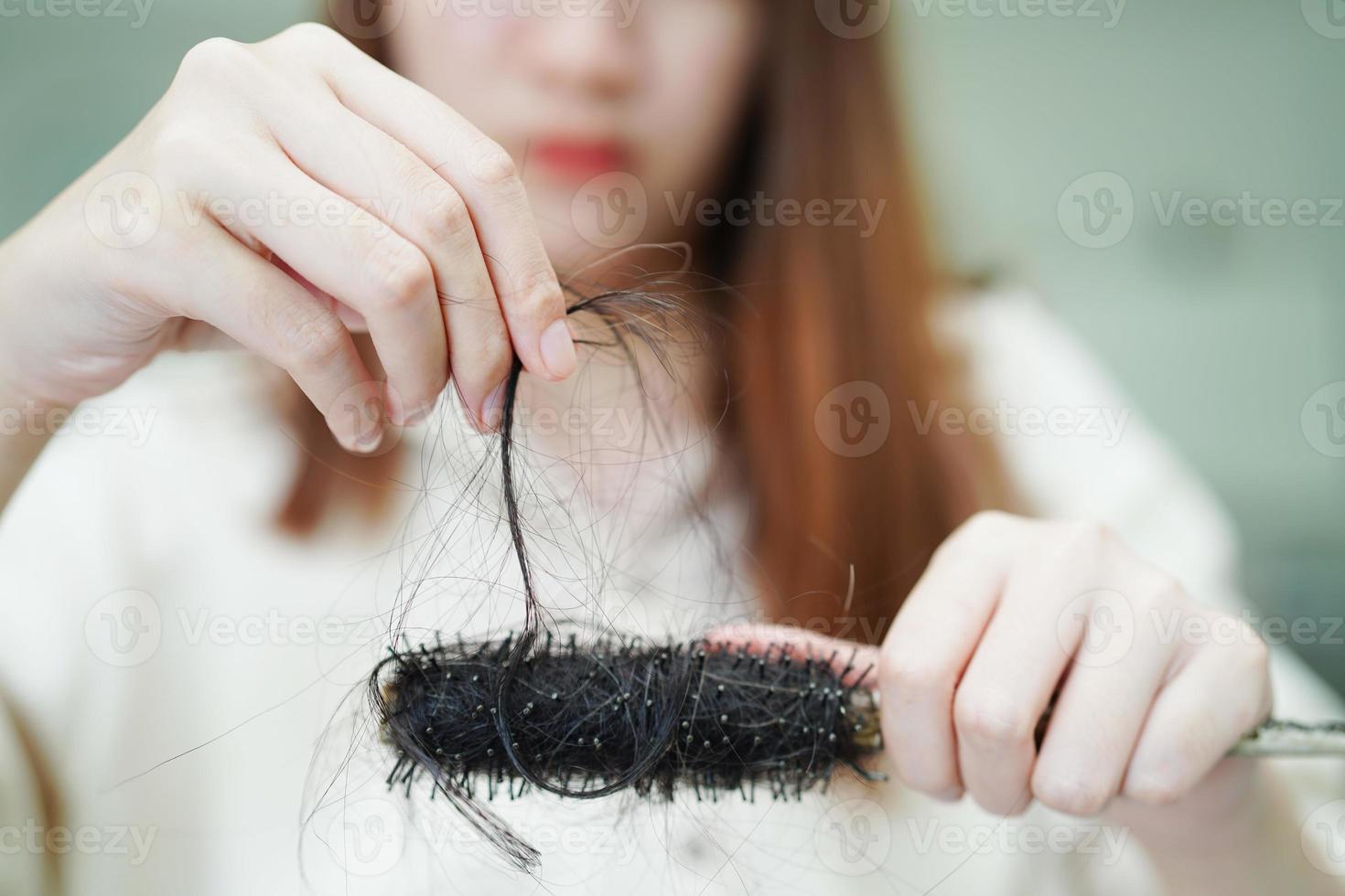 une femme asiatique a un problème avec la perte de cheveux longs attachée à la brosse à peigne. photo