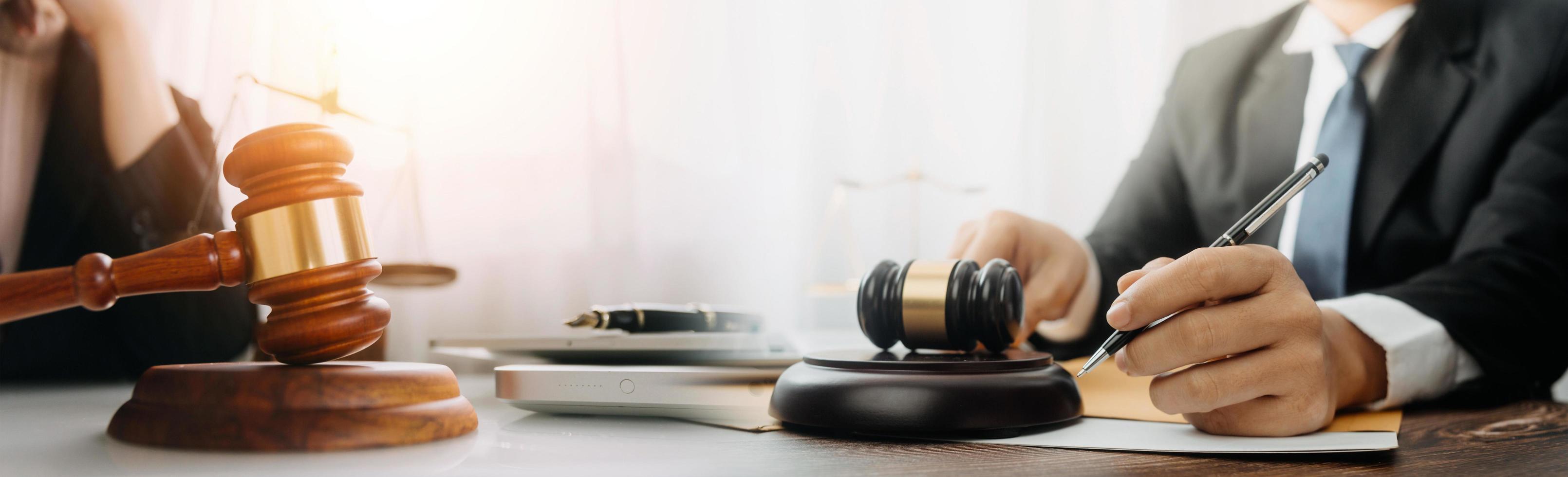 concept de justice et de droit. juge masculin dans une salle d'audience avec le marteau, travaillant avec, clavier d'ordinateur et d'accueil, lunettes, sur table à la lumière du matin photo