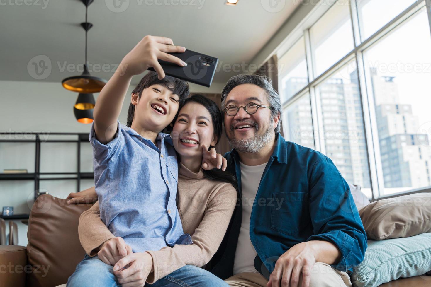 famille souriant à la caméra. famille heureuse prenant un selfie, souriant à un téléphone à la maison. photo