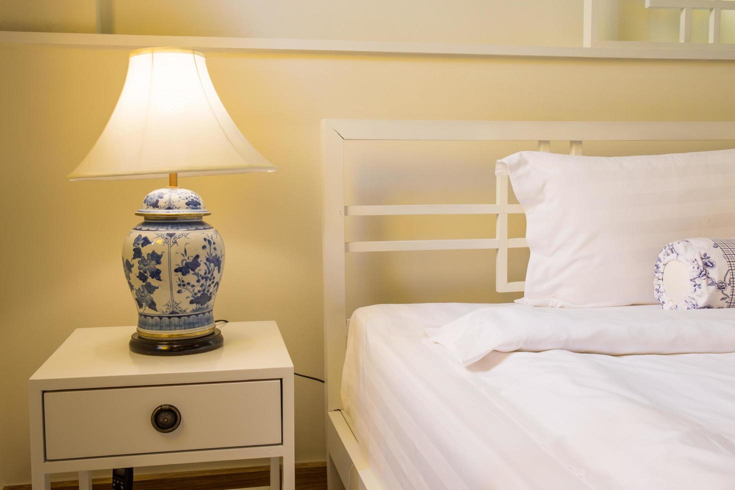 intérieur de chambre confortable avec oreillers et lampe rétro sur table de chevet et lumière chaude photo