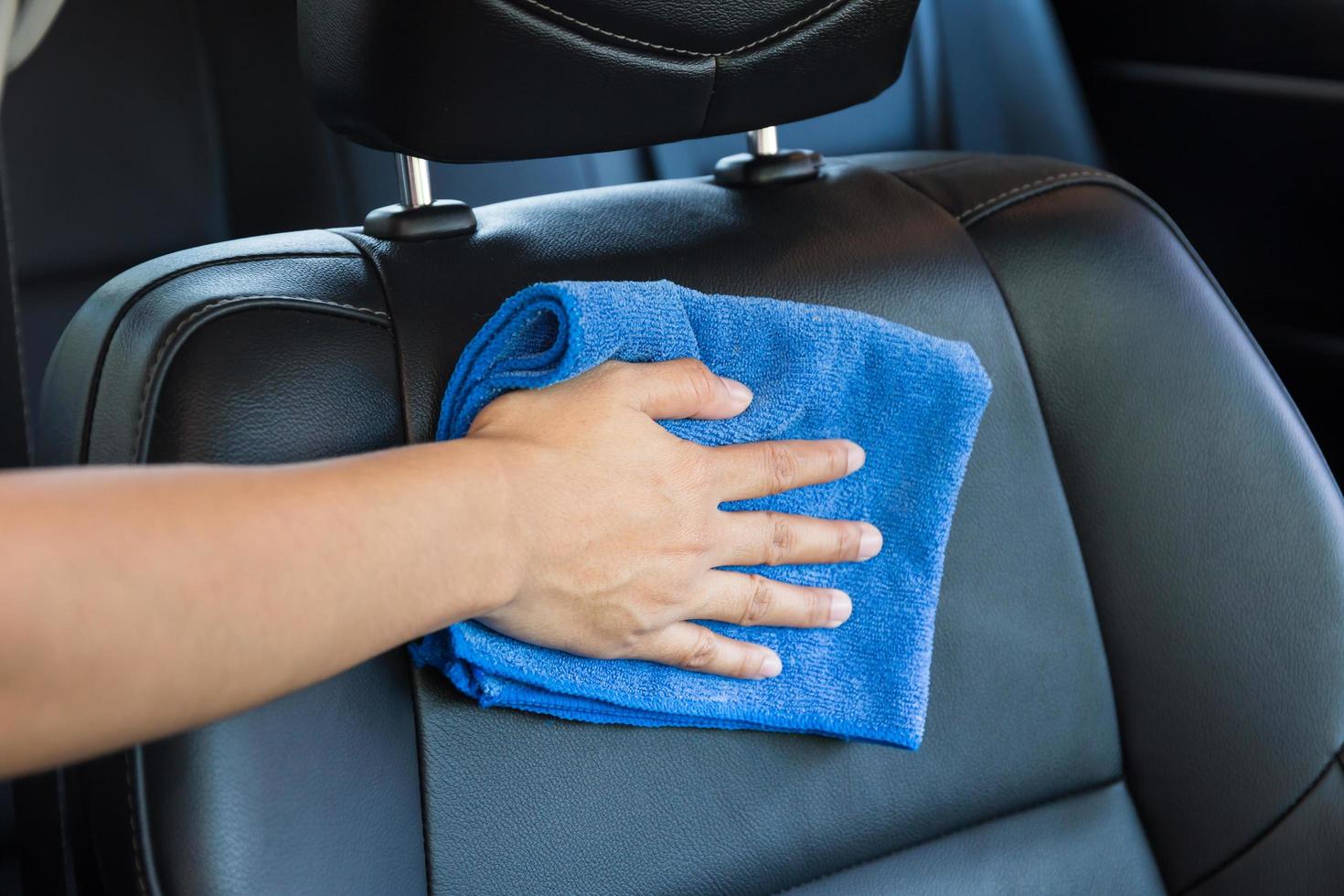 main avec un chiffon en microfibre nettoyant l'intérieur de la voiture moderne. photo