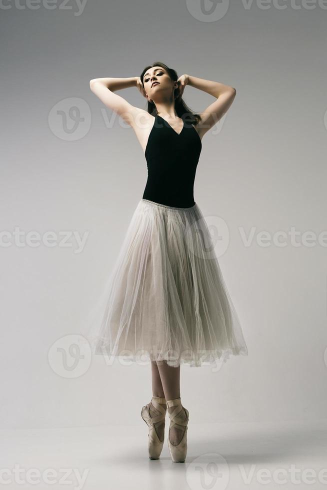 ballerine en body et jupe blanche improvise une chorégraphie classique et moderne dans un studio photo