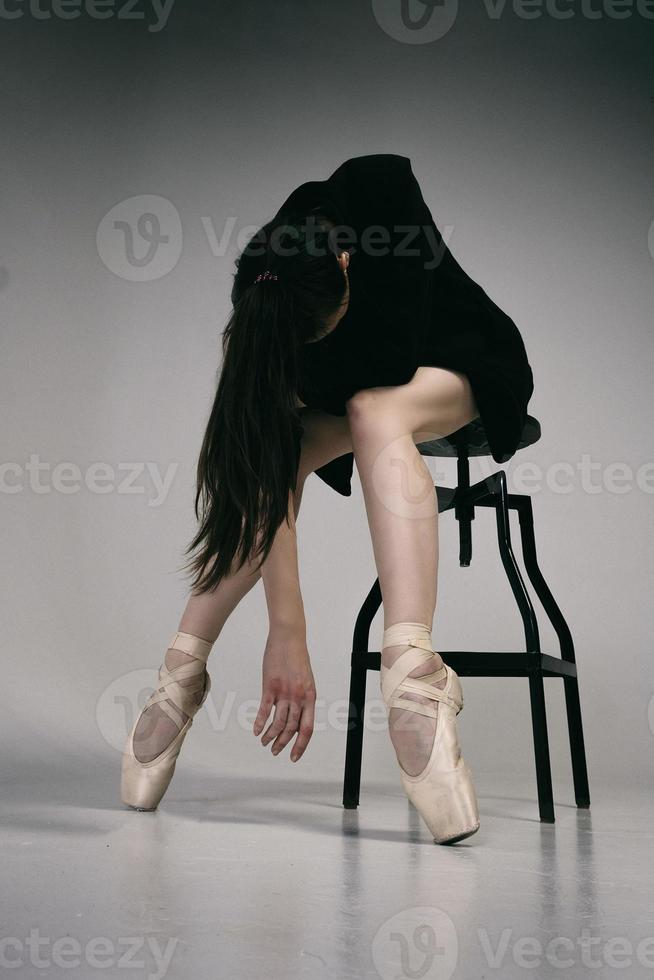 ballerine en body et veste noire improvise une chorégraphie classique et moderne dans un studio photo