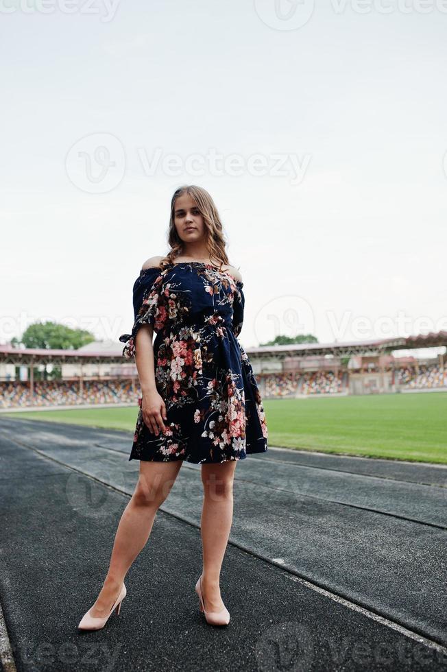 portrait d'une fille fabuleuse en robe et talons hauts sur la piste du stade. photo