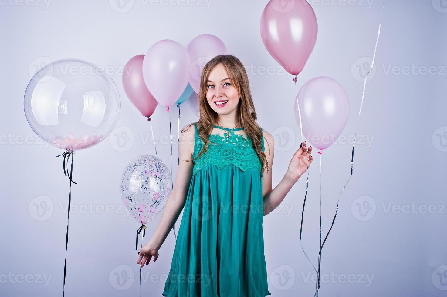 fille heureuse en robe turquoise verte avec des ballons colorés isolés sur blanc. célébrer le thème de l'anniversaire. photo