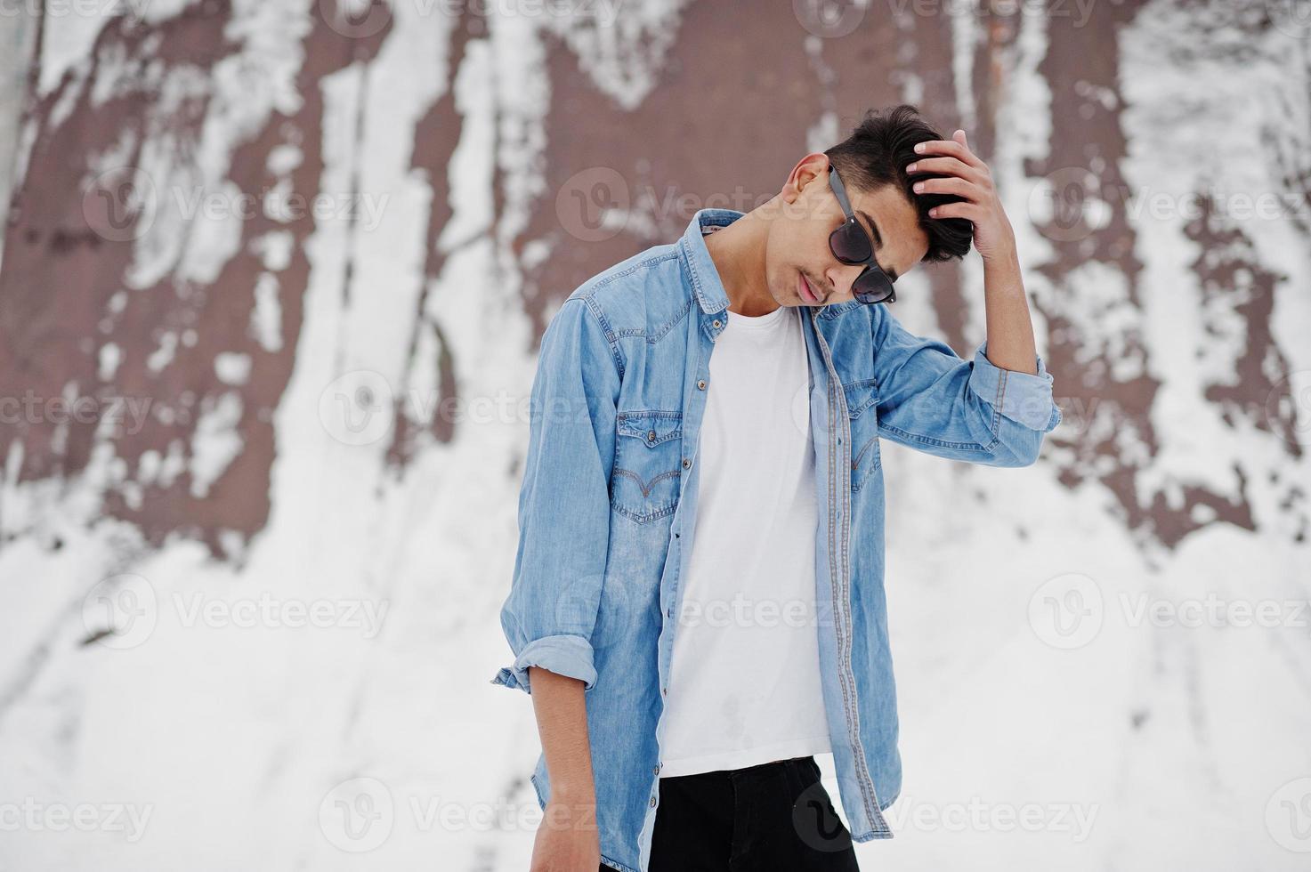 jeune homme indien décontracté en chemise de jeans bleu et lunettes de soleil posées le jour de l'hiver. photo