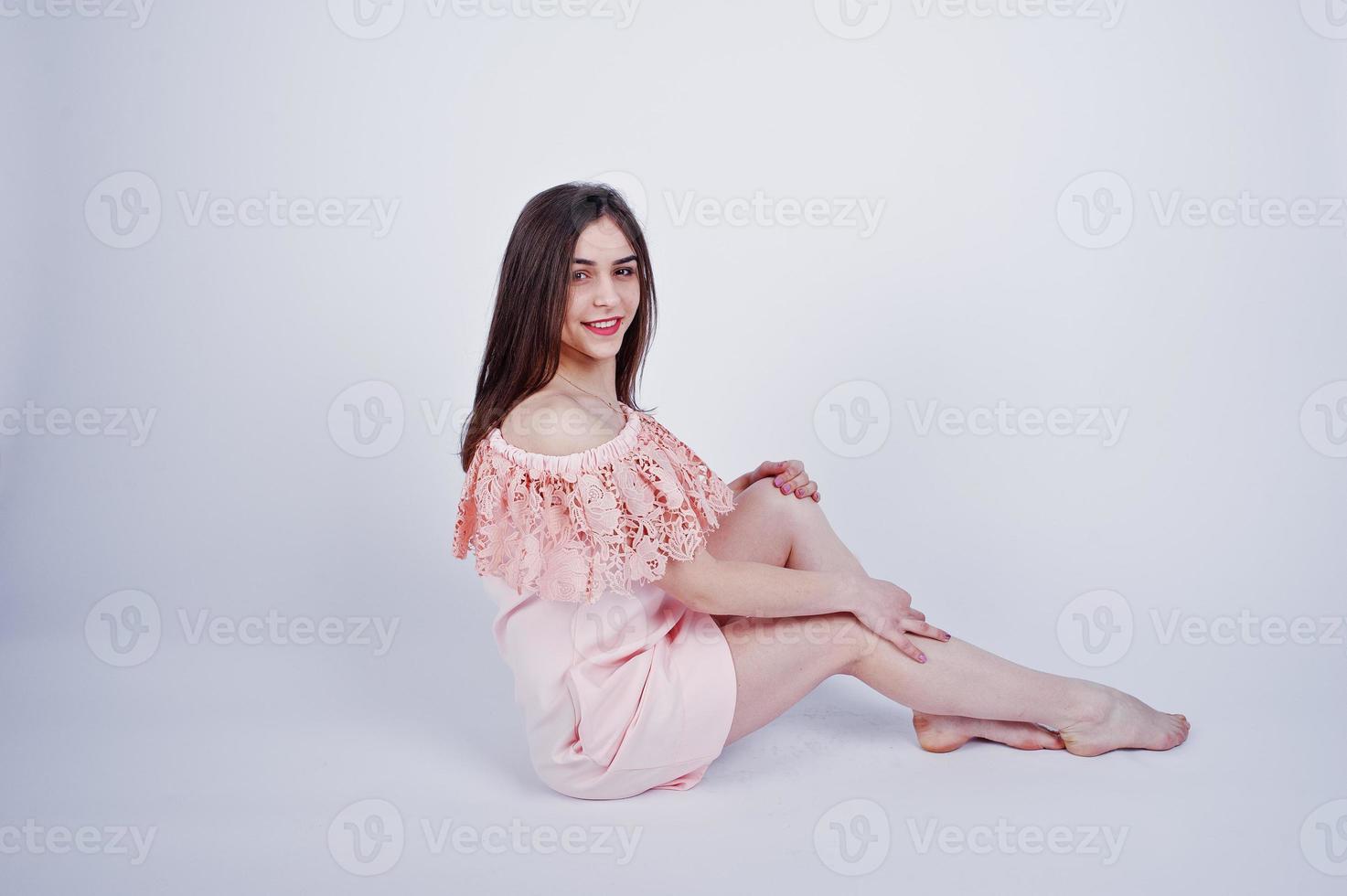 portrait d'une femme à la mode en robe rose assise et posant sur le sol dans le studio. photo