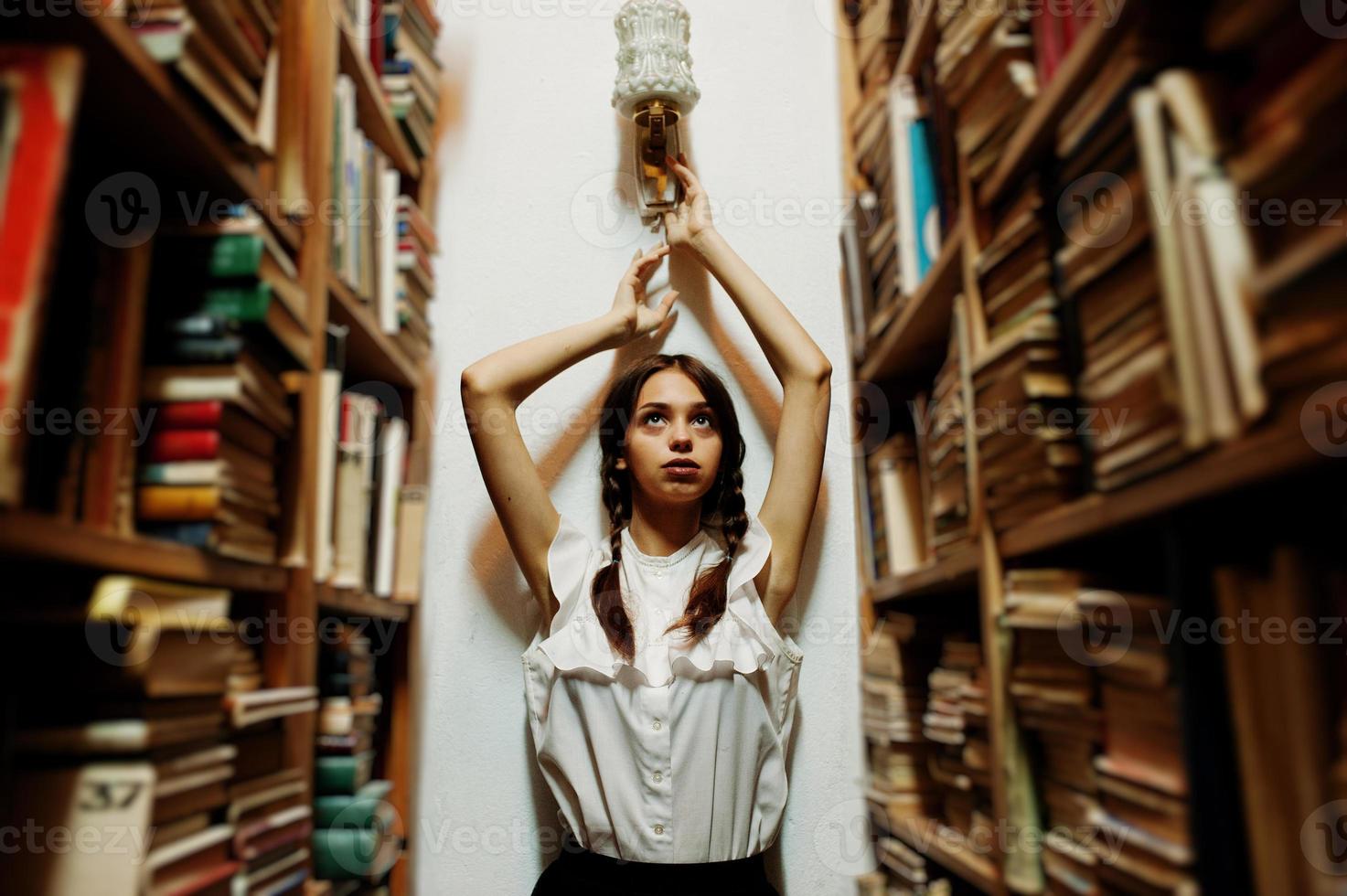 fille avec des nattes en blouse blanche à l'ancienne bibliothèque. photo