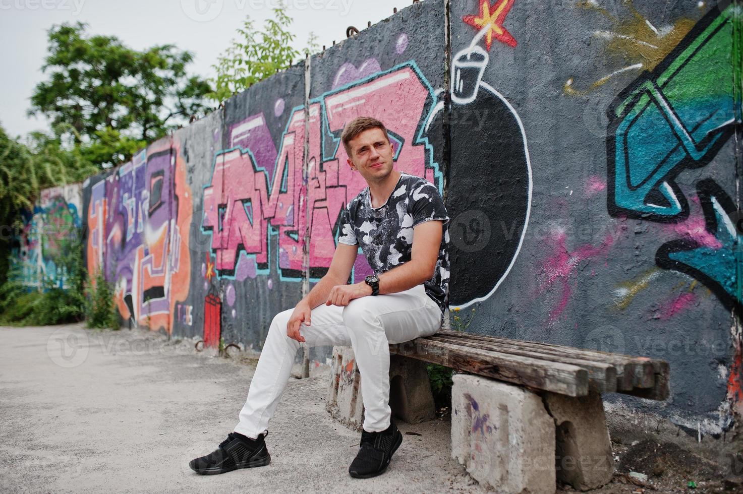 portrait de style de vie d'un bel homme posant dans la rue de la ville avec un mur de graffitis. photo