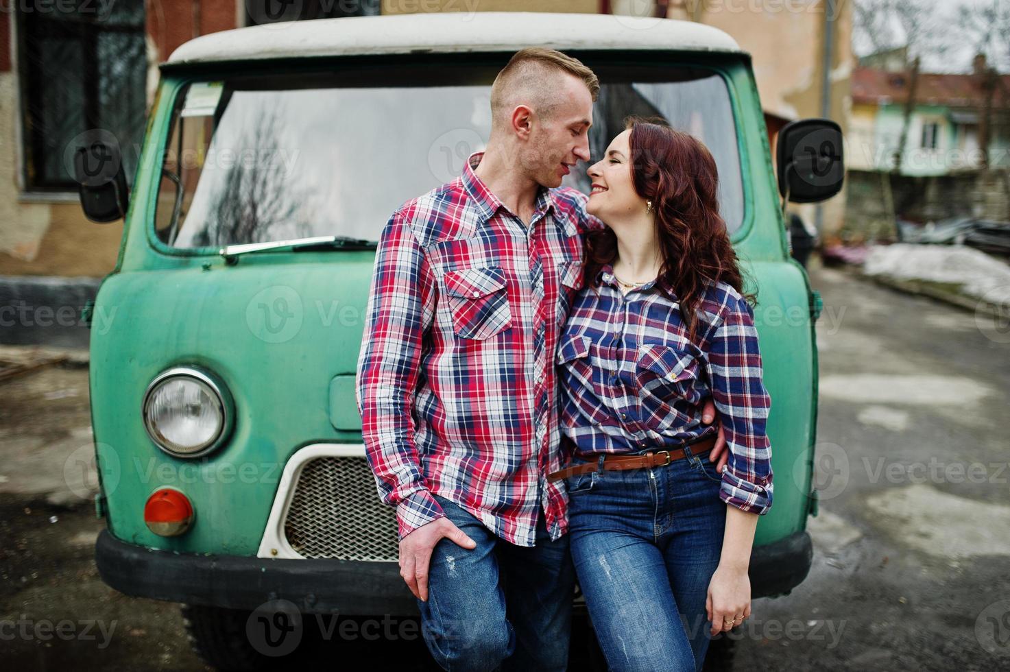 couple élégant portant une chemise à carreaux amoureux ensemble contre une vieille fourgonnette. photo