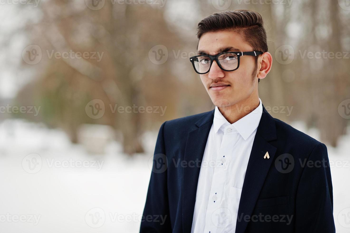 portrait en gros plan d'un étudiant indien élégant en costume et lunettes posé à la journée d'hiver en plein air. photo