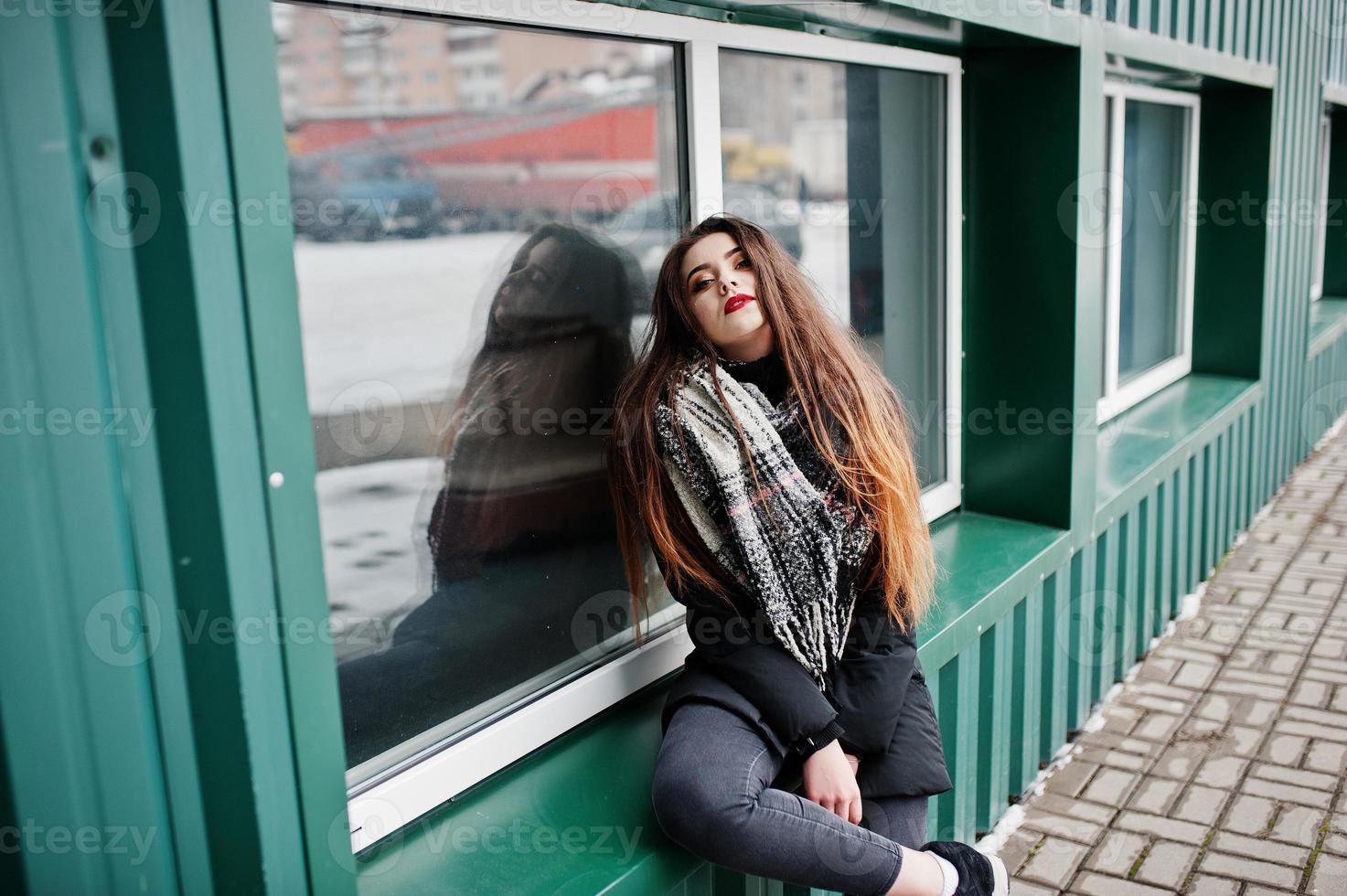 brune élégante fille décontractée en écharpe contre un mur métallique vert. photo