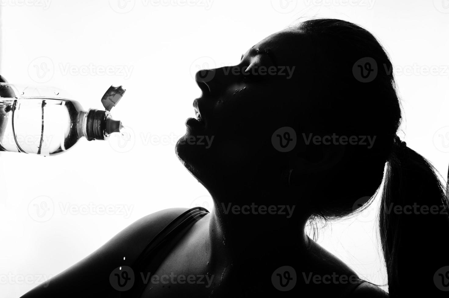 portrait noir et blanc d'une jeune femme de fitness séduisante et joyeuse en haut avec une bouteille d'eau isolée sur fond blanc. photo