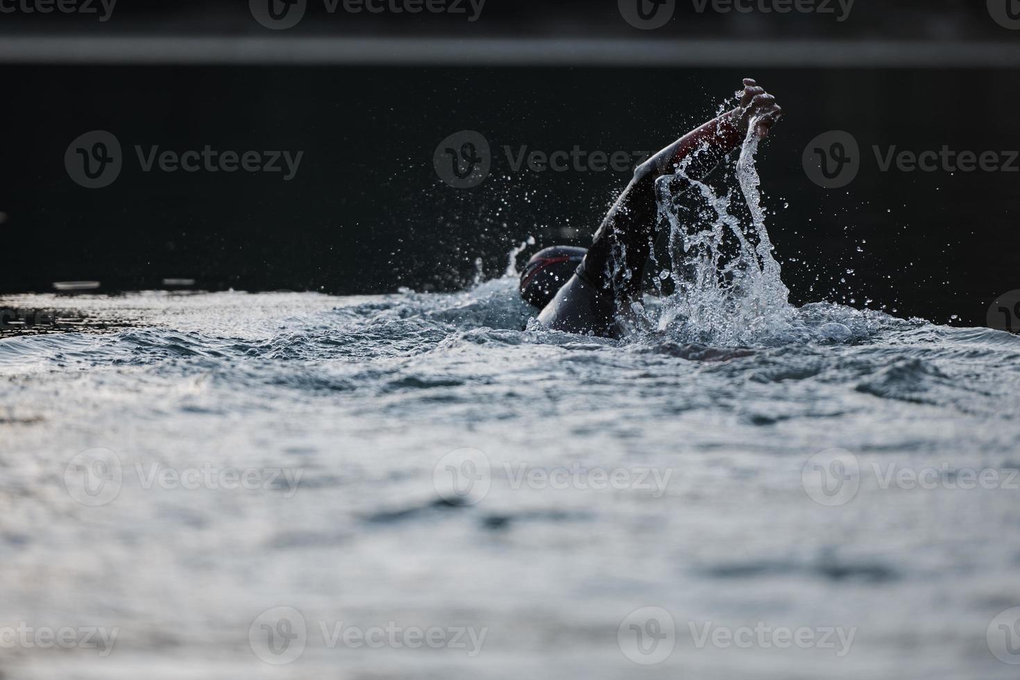 athlète de triathlon nageant sur le lac au lever du soleil portant une combinaison de plongée photo