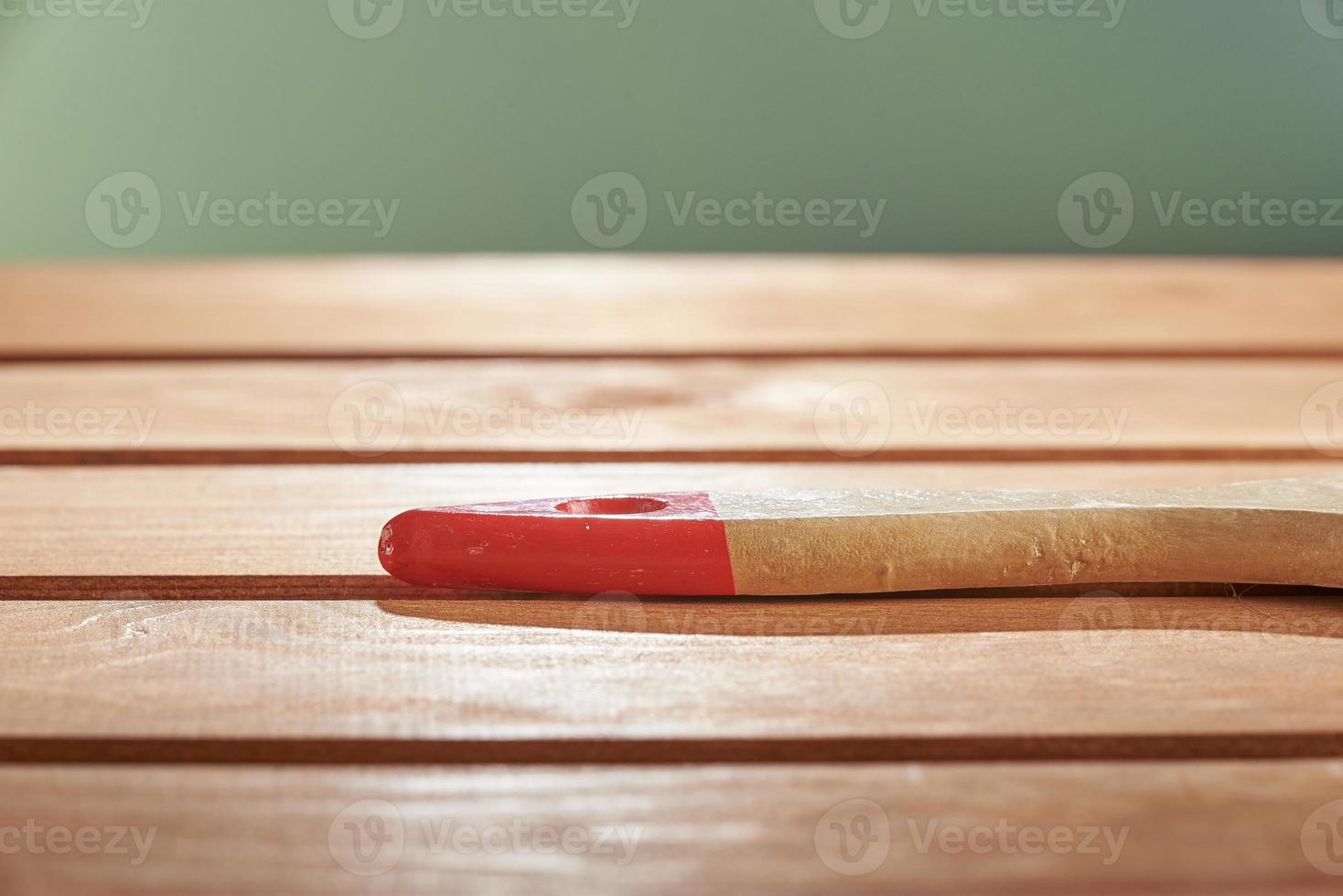 surface en bois fraîchement peinte sur fond vert. le fond est flou. le manche en bois de la brosse sur le sol. photo