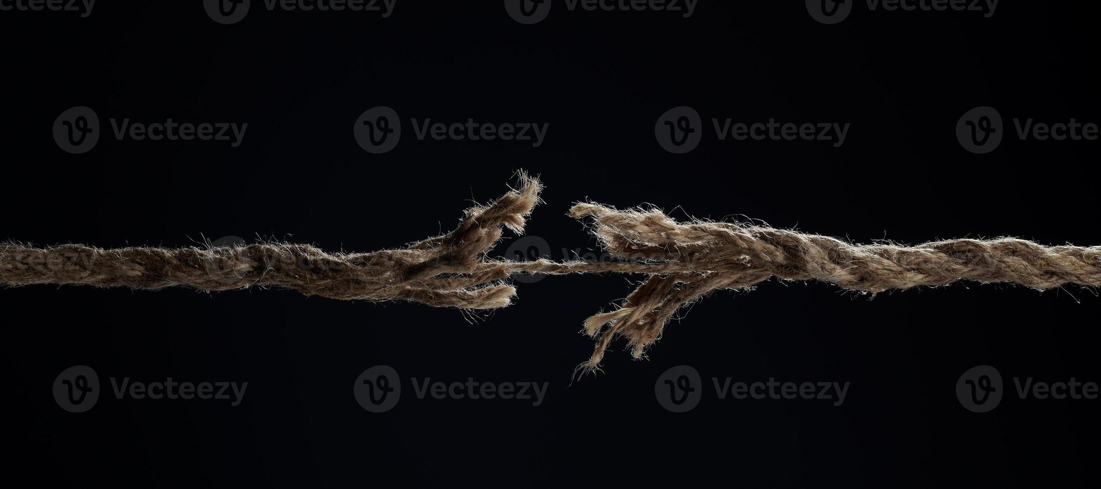 une corde tendue se casse sur un fond noir. la notion de divorce. une rupture dans une relation. photo