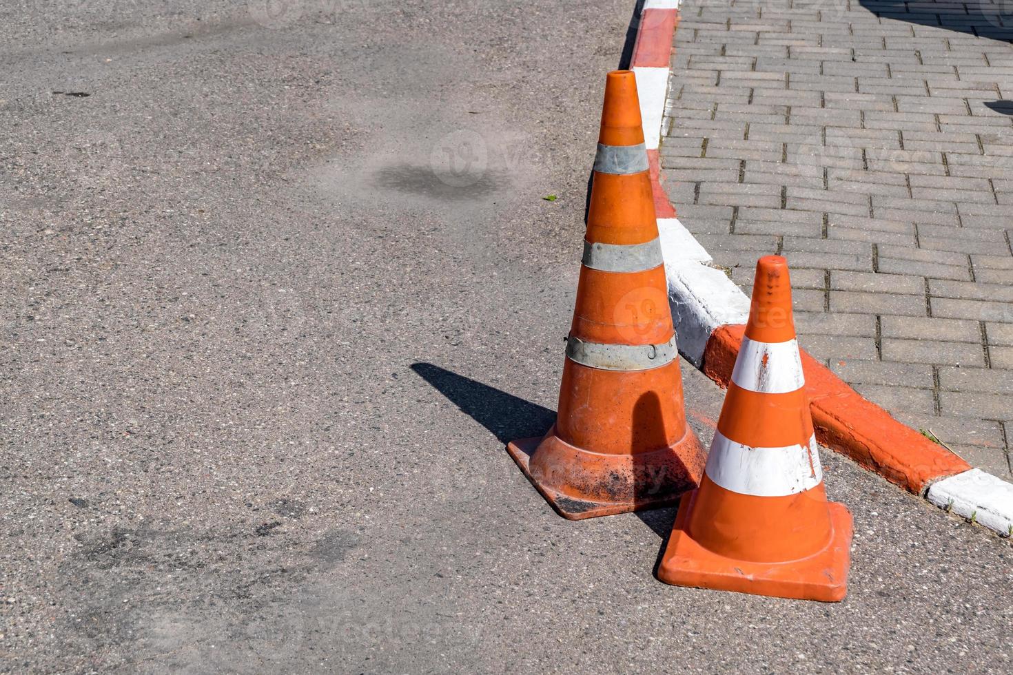 Cône de danger de circulation orange blanc sur la réparation de routes asphaltées photo