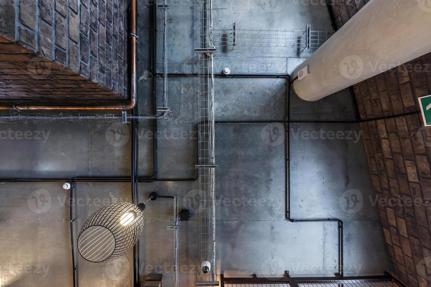 plafond en béton gris avec spots halogènes et lampes edison dans un bureau loft avec climatisation et tuyau de ventilation orange. regardant vers le haut photo