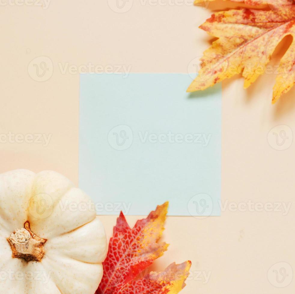 mise à plat d'un cahier vierge d'espace de travail minimal avec des feuilles d'automne et de la citrouille sur fond jaune, concept d'automne et d'action de grâces photo