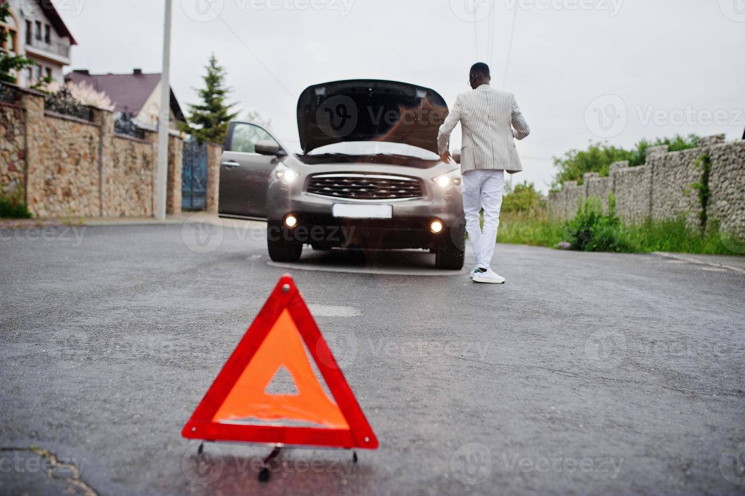 triangle d'avertissement rouge d'urgence sur le panneau de signalisation voiture suv cassée d'un homme africain. photo