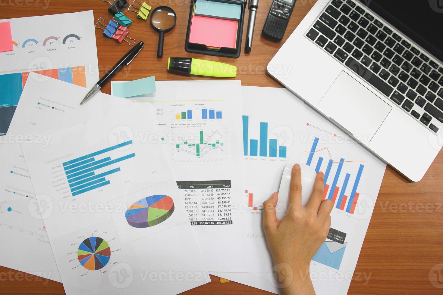 vue de dessus des femmes d'affaires travaillant des rapports financiers avec un ordinateur portable et divers blocs-notes sur une table de bureau en bois. photo