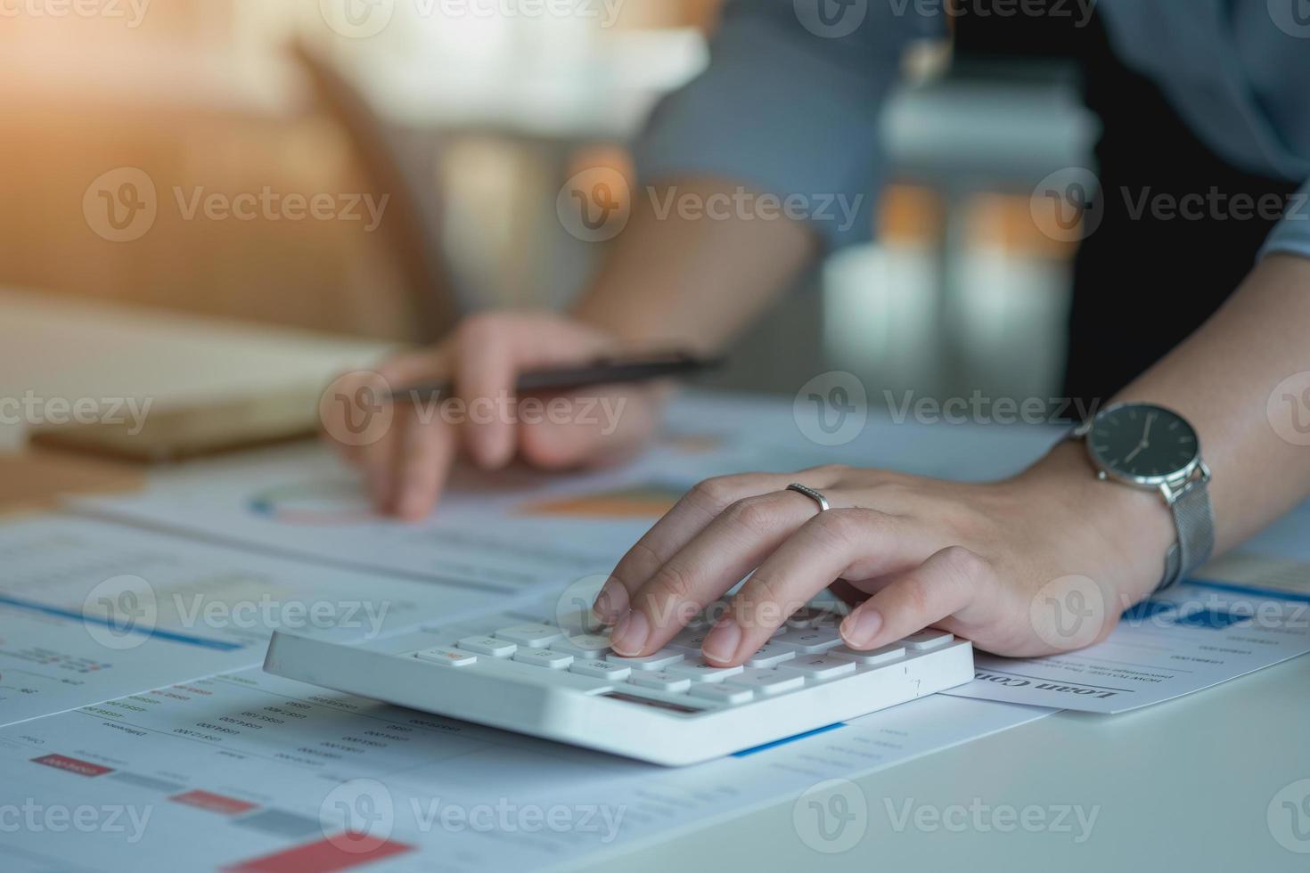 portrait d'une femme comptable utilisant une calculatrice et un ordinateur portable pour calculer le solde à l'aide de graphiques pour les clients. photo