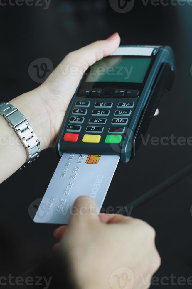 une femme utilisant une machine à carte de crédit manuelle pour vendre des produits dans la boutique. concept de dépenses par carte de crédit. photo