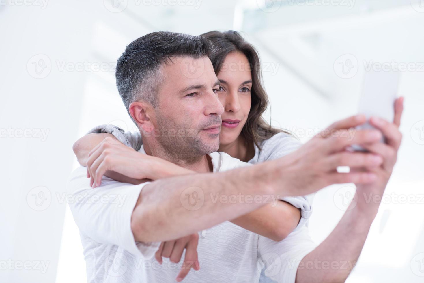 couple heureux utilisant un téléphone portable à la maison photo