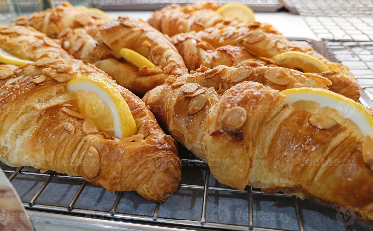 fermer. croissant aux tranches d'amandes et de citron sur le plateau. photo