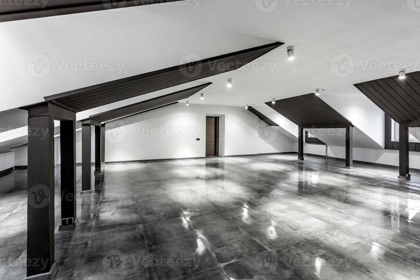 Intérieur vide de la chambre mansardée loft non meublé avec colonnes en bois et sol en béton humide au niveau du toit en couleur de style noir et blanc photo