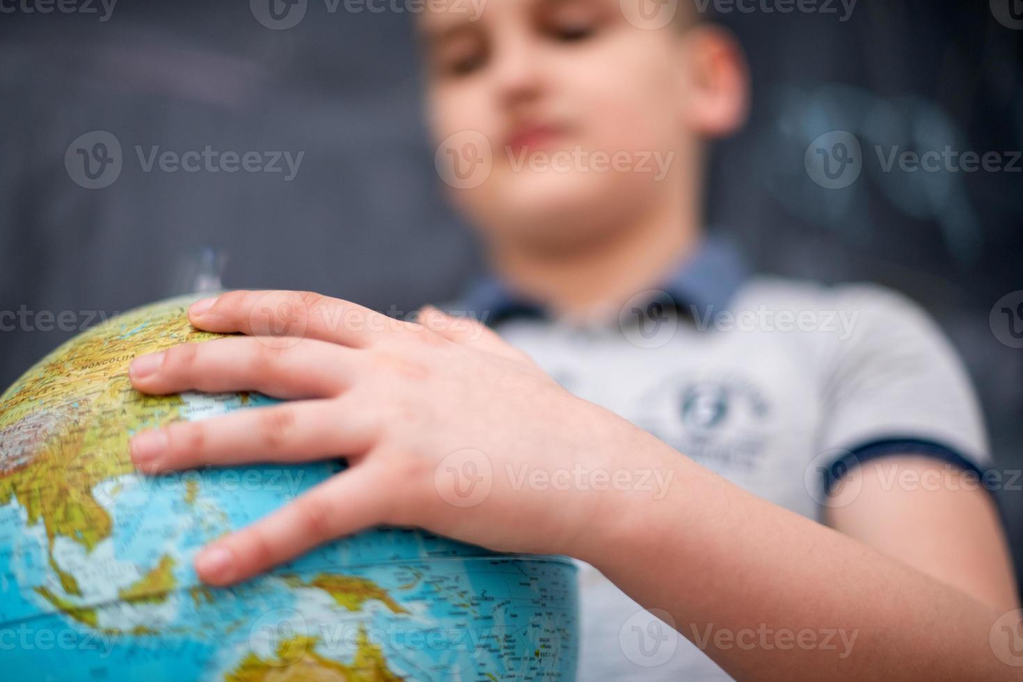 garçon utilisant un globe terrestre devant un tableau photo