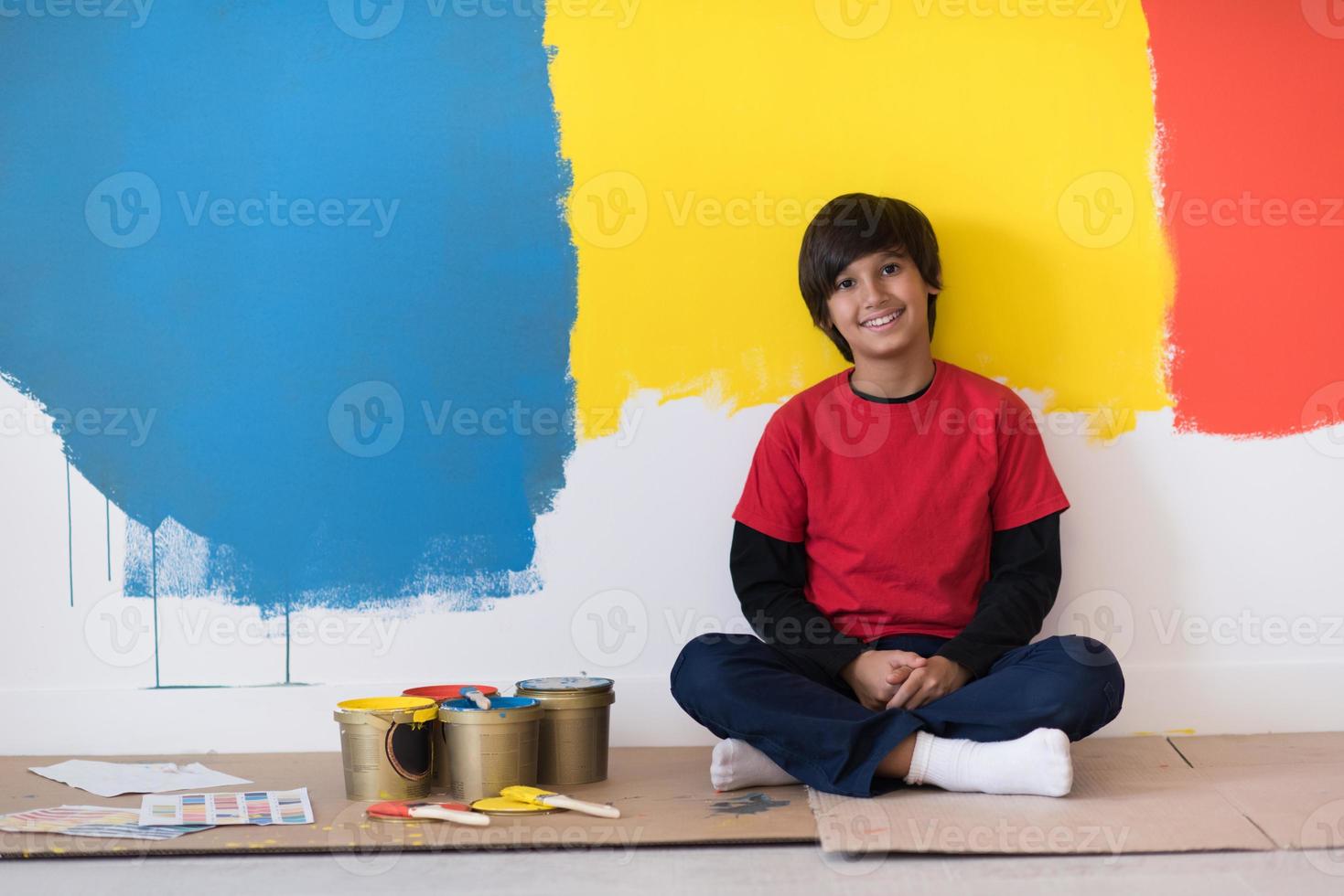 jeune garçon peintre se reposant après avoir peint le mur photo