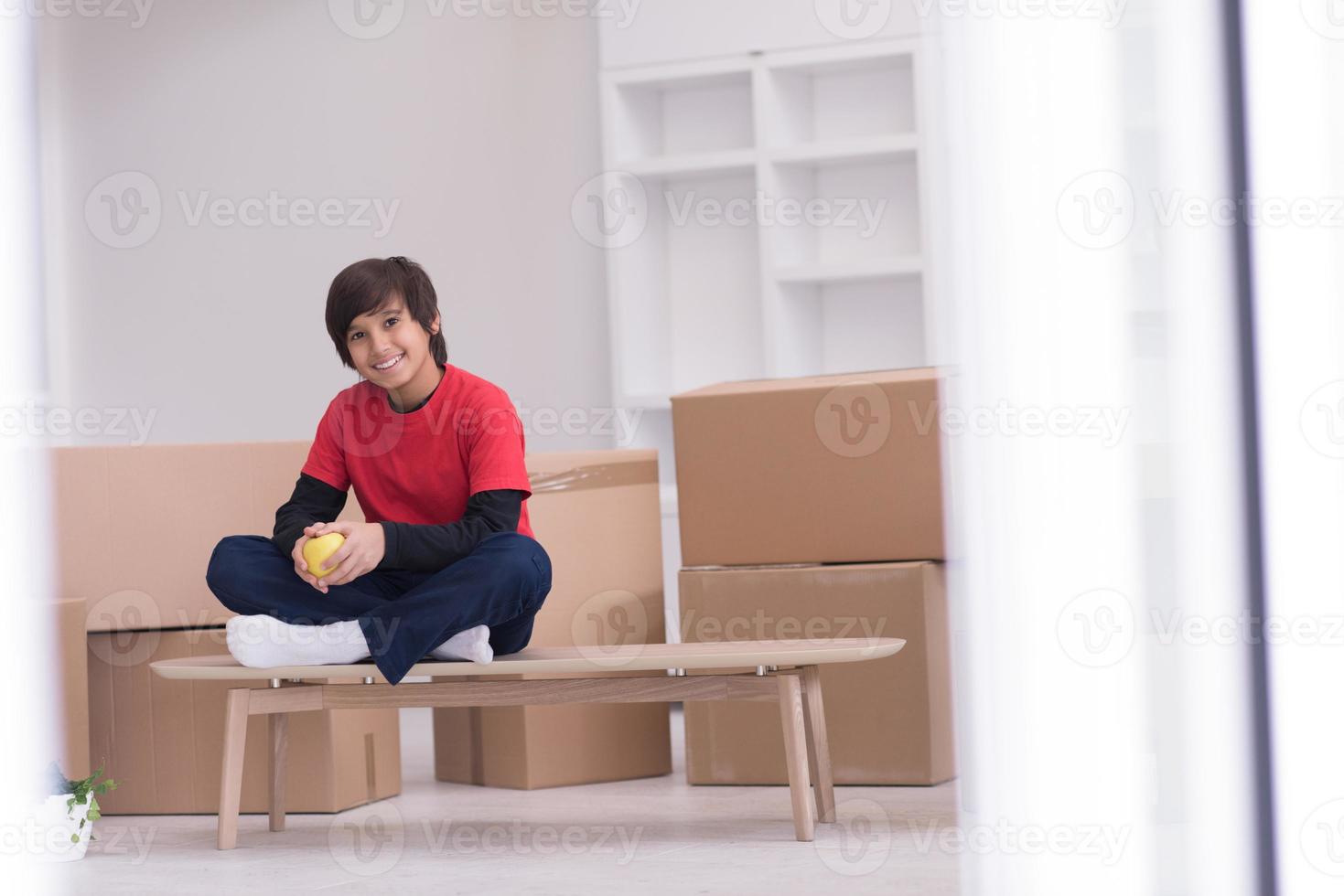garçon assis sur la table avec des cartons autour de lui photo