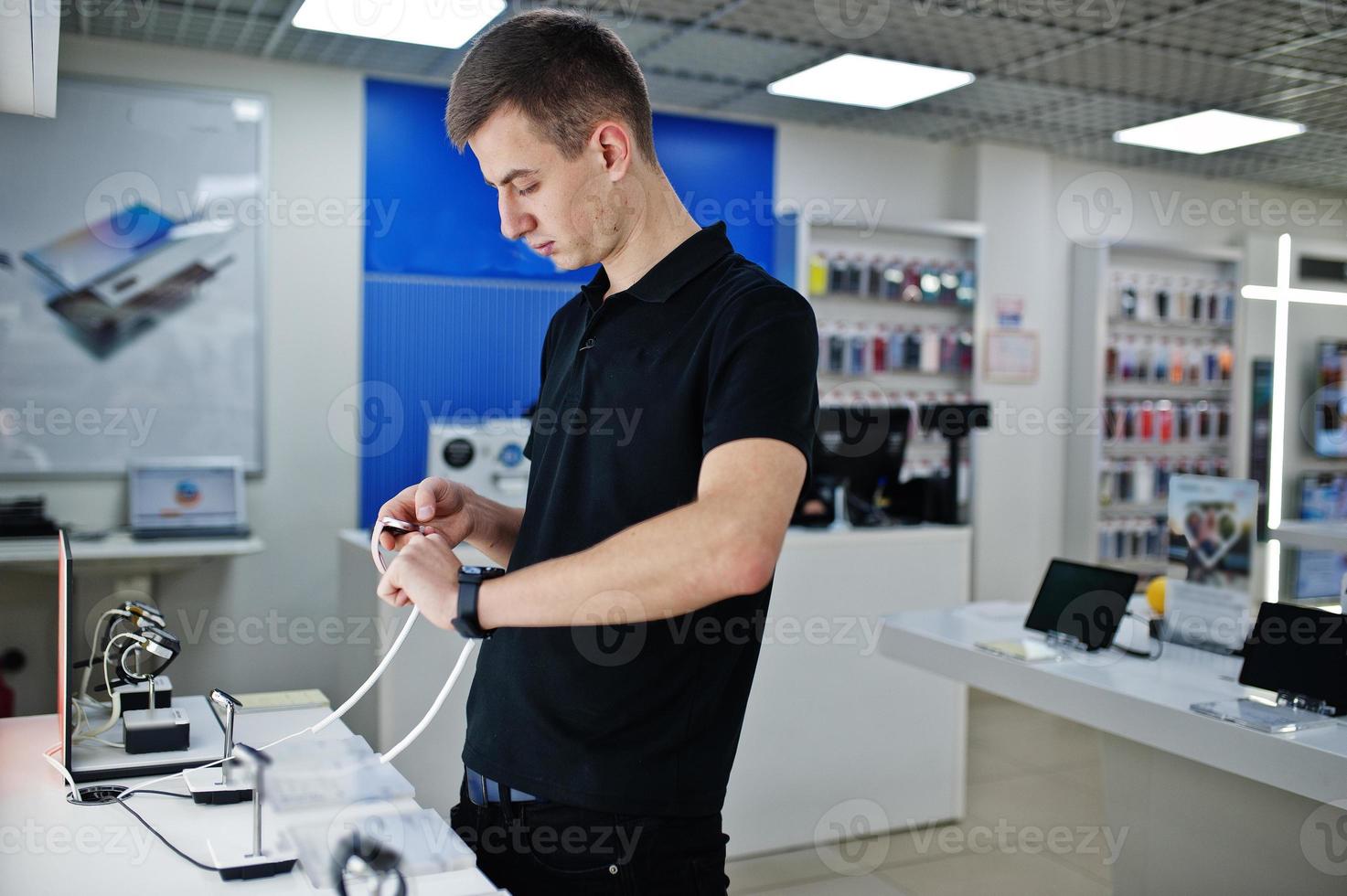 vendeur homme consultant professionnel en téléphonie mobile dans un magasin de technologie ou un magasin vérifier les nouvelles montres intelligentes. photo