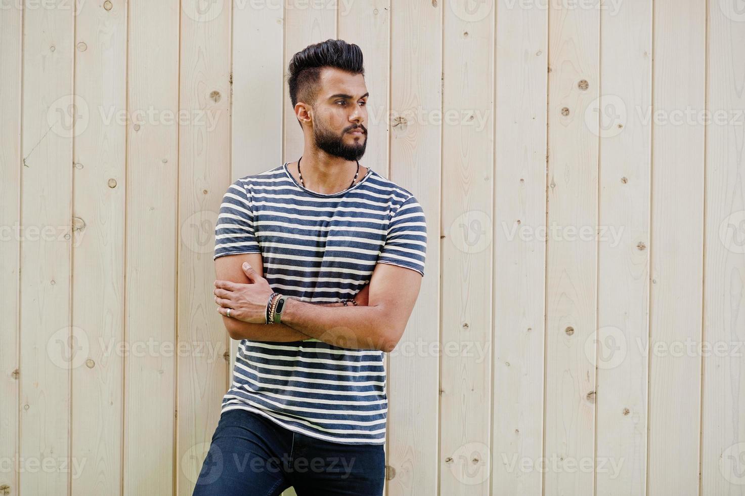 beau grand modèle d'homme à barbe arabe à chemise dépouillée posé en plein air sur fond de bois. mec arabe à la mode. photo