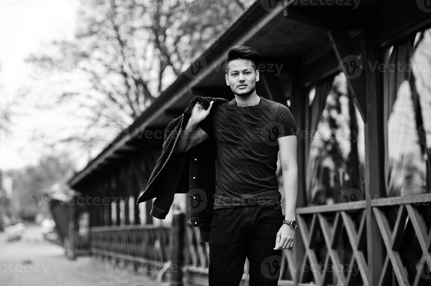 bel homme indien à la mode en chemise noire avec veste posée en plein air. photo